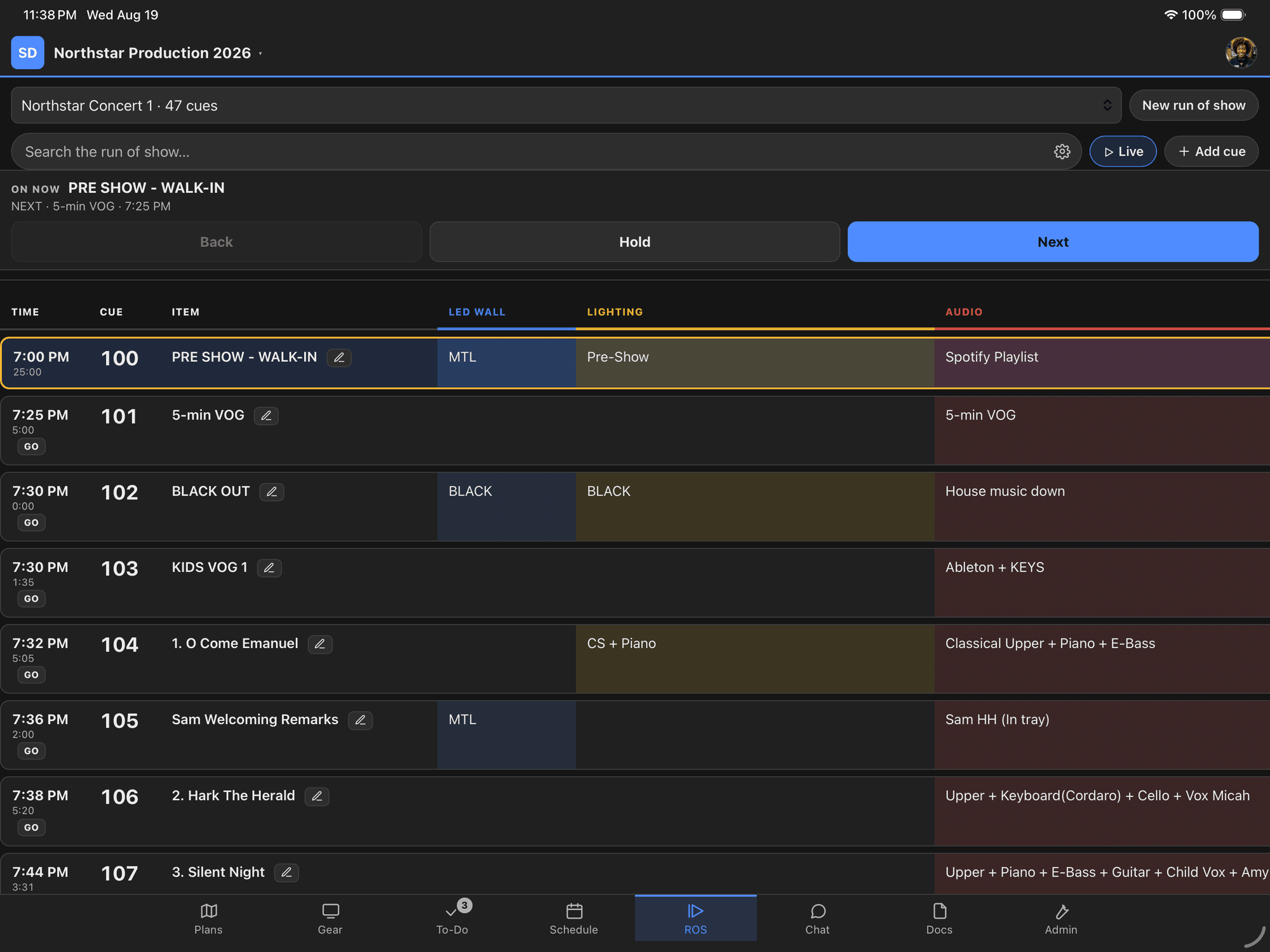 An iPad in landscape showing the run of show being called live — cue numbers and clock times down the left, a column each for LED wall, lighting and audio, and Back, Hold and Next across the top.